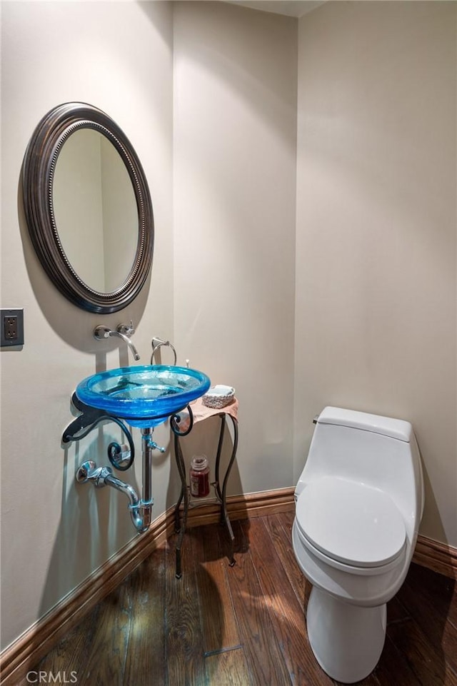 bathroom featuring toilet, baseboards, and wood finished floors