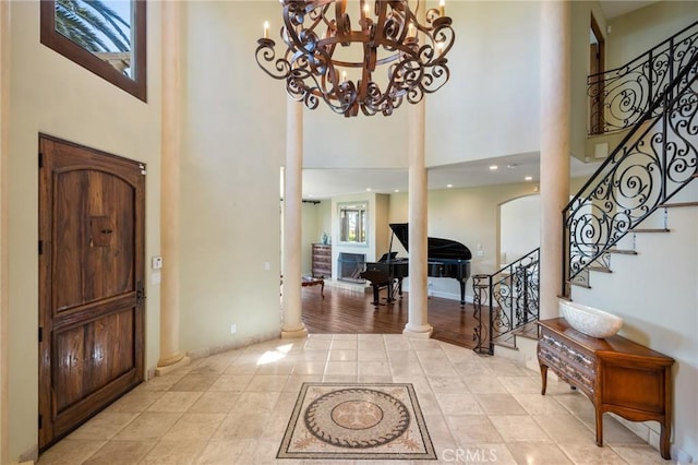 foyer entrance featuring ornate columns, a high ceiling, light tile patterned floors, and stairs