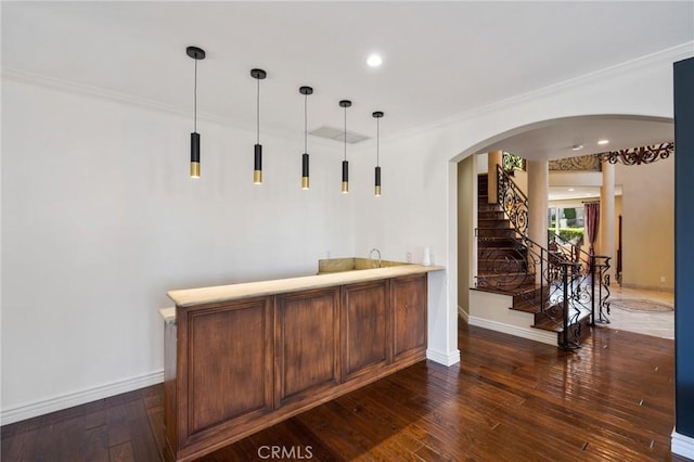 bar featuring baseboards, decorative light fixtures, dark wood-style flooring, crown molding, and stairway