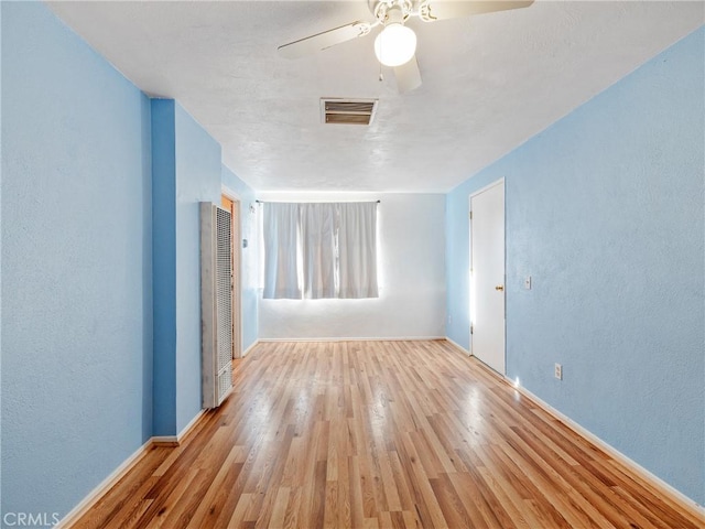 14435 Hopi Rd, Apple Valley, CA 92307 - spare room featuring ceiling fan, baseboards, a heating unit, and wood finished floors