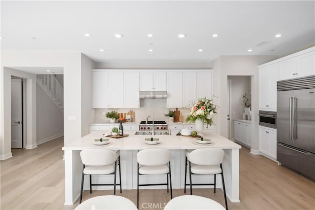 108 Hyperion, Irvine, CA 92618 - kitchen with a sink, a breakfast bar area, stainless steel appliances, a center island with sink, and under cabinet range hood