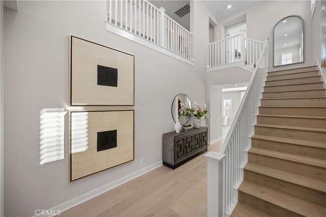 108 Hyperion, Irvine, CA 92618 - staircase featuring baseboards, a healthy amount of sunlight, wood finished floors, and a high ceiling