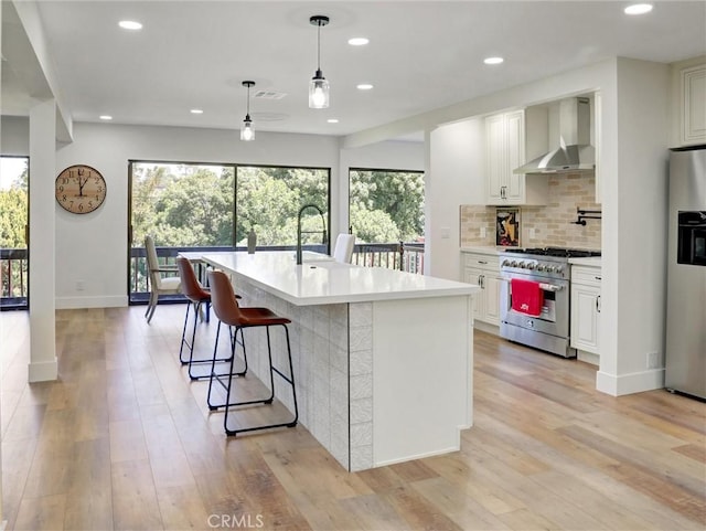 kitchen with appliances with stainless steel finishes, wall chimney range hood, visible vents, and a healthy amount of sunlight