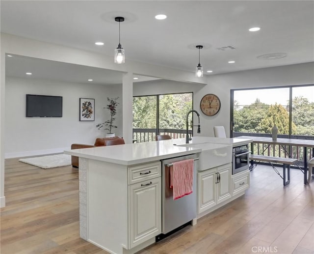 kitchen featuring light countertops, appliances with stainless steel finishes, decorative light fixtures, and a sink