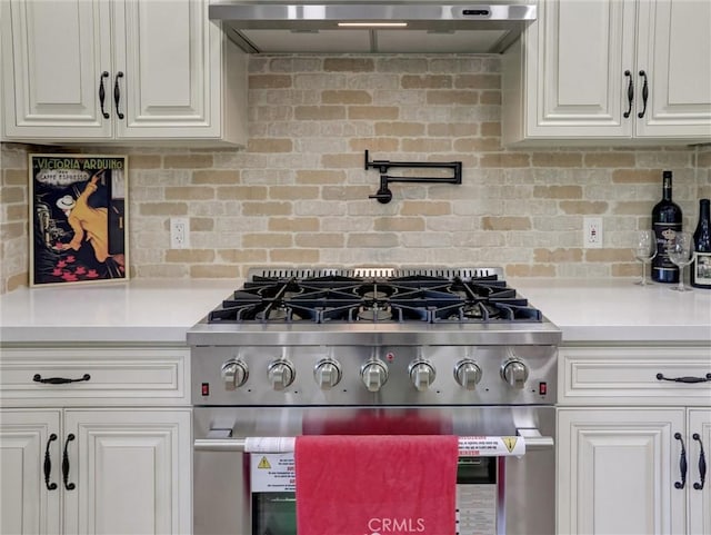 kitchen with high end stainless steel range oven, wall chimney range hood, light countertops, white cabinets, and decorative backsplash