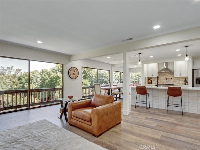 living area with light wood-style floors, visible vents, and recessed lighting