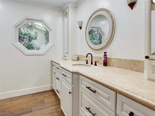 bathroom with vanity, baseboards, ornamental molding, and wood finished floors