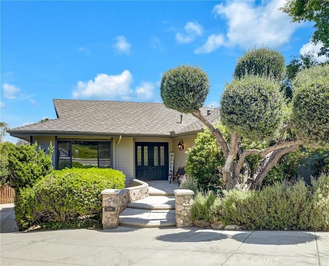 view of front of home with french doors and a shingled roof