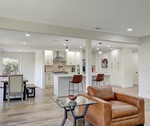 living area featuring light wood finished floors, baseboards, and recessed lighting