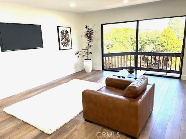 living room with wood finished floors, baseboards, and recessed lighting