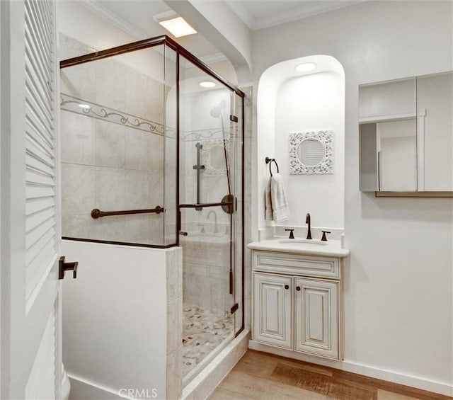 full bathroom featuring crown molding, a stall shower, wood finished floors, and vanity