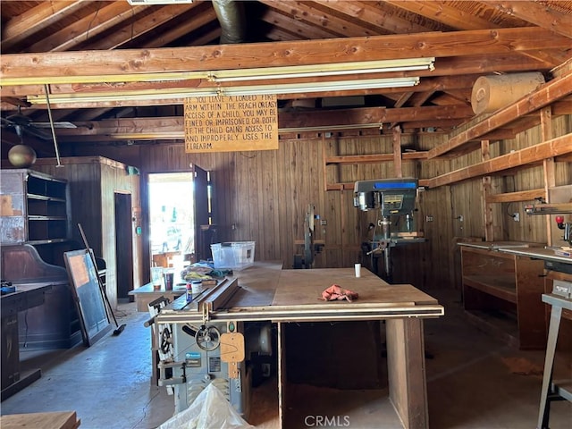 game room featuring a workshop area, wooden walls, concrete floors, and vaulted ceiling