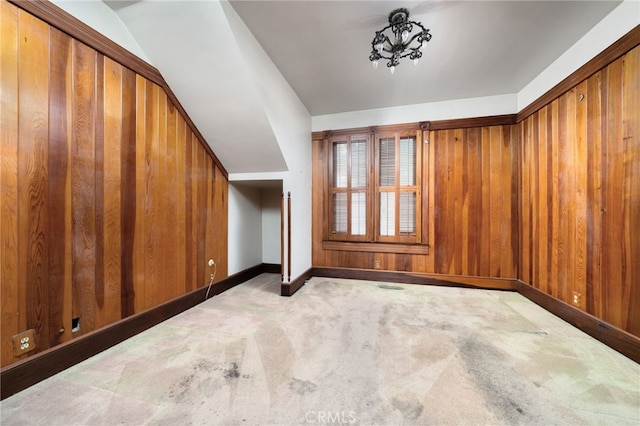 bonus room with baseboards, wooden walls, and carpet