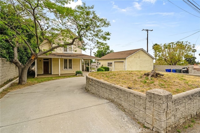 view of front of property with a porch, fence, an outbuilding, a garage, and driveway