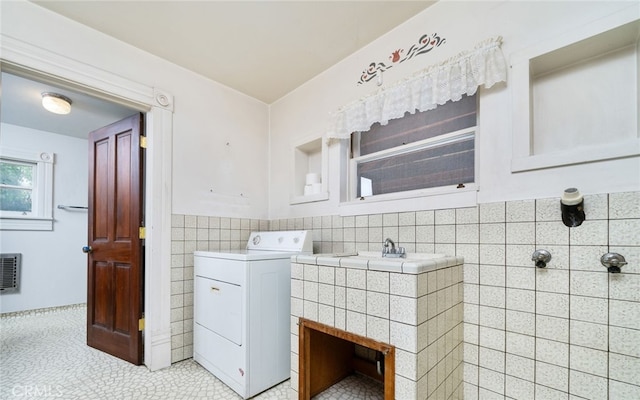 laundry room featuring tile walls, light tile patterned floors, laundry area, a wainscoted wall, and washer / clothes dryer