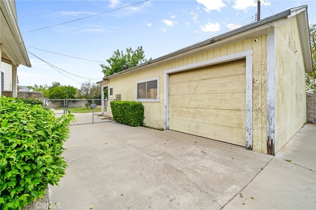 detached garage with a gate, fence, and concrete driveway
