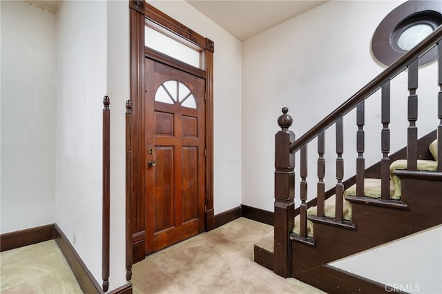 carpeted entrance foyer featuring baseboards and stairs
