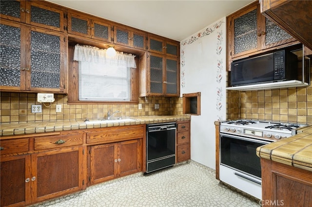 kitchen with black appliances, tile countertops, decorative backsplash, and a sink