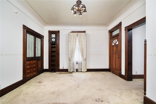 entryway with a healthy amount of sunlight, baseboards, an inviting chandelier, and carpet