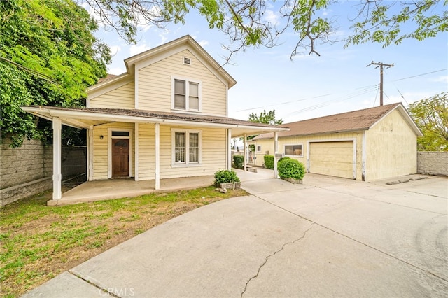 traditional home with a porch, an outdoor structure, a garage, and fence