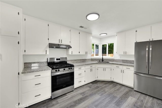 217 N Sacramento, Willows, CA 95988 - kitchen featuring appliances with stainless steel finishes, a sink, under cabinet range hood, white cabinetry, and wood finished floors