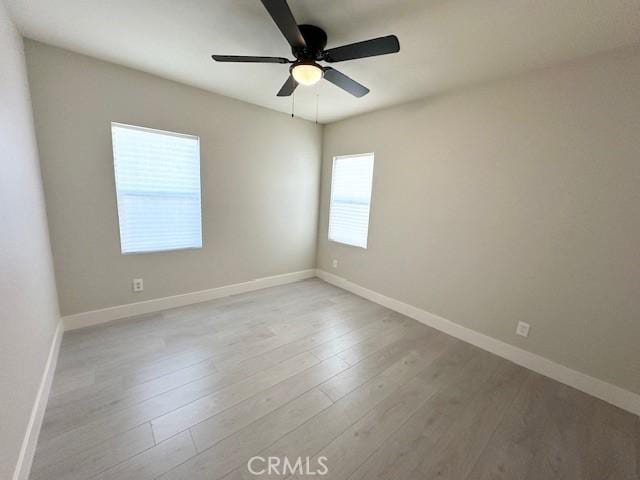 spare room featuring baseboards, wood finished floors, and ceiling fan
