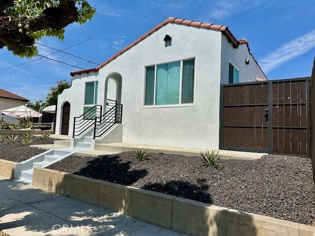 mediterranean / spanish home with a gate, a tiled roof, stucco siding, and fence