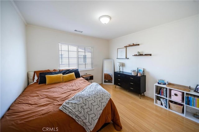 bedroom featuring light wood-type flooring, crown molding, and visible vents