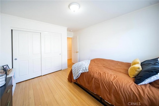 bedroom featuring light wood-style floors, a closet, and ornamental molding