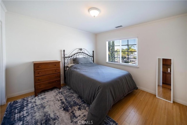 bedroom featuring crown molding, visible vents, baseboards, and light wood-type flooring