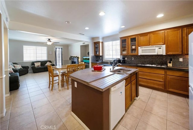 kitchen with brown cabinets, a sink, white appliances, and dark countertops