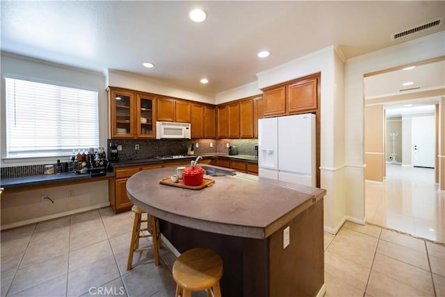 kitchen with white appliances, brown cabinetry, visible vents, a sink, and backsplash
