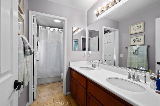 bathroom with a sink, tile patterned floors, toilet, and double vanity