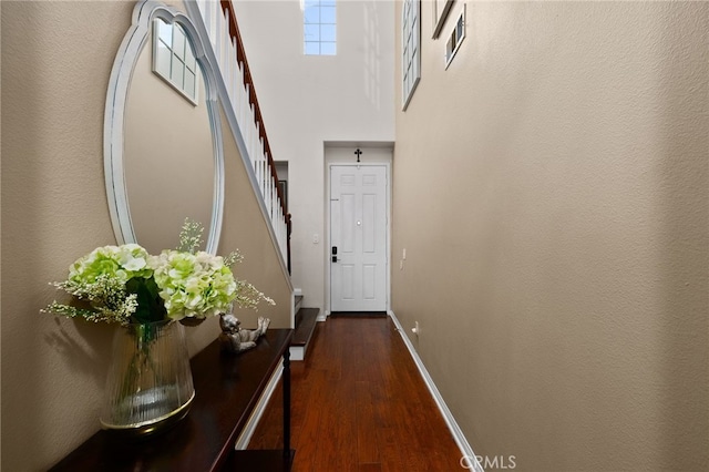 doorway with dark wood finished floors, a towering ceiling, visible vents, stairway, and baseboards