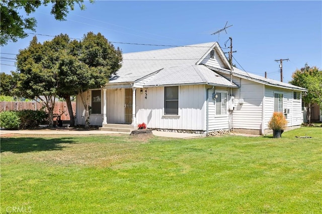 bungalow-style home with a shingled roof, fence, and a front lawn