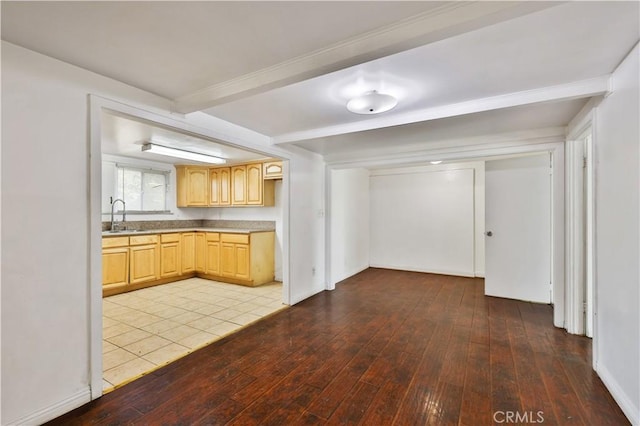 kitchen featuring a sink, light countertops, light brown cabinetry, beam ceiling, and hardwood / wood-style floors