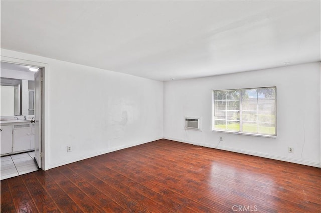 unfurnished living room featuring baseboards, an AC wall unit, and hardwood / wood-style flooring