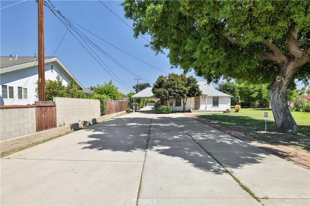 view of front of home with concrete driveway, a front yard, and fence