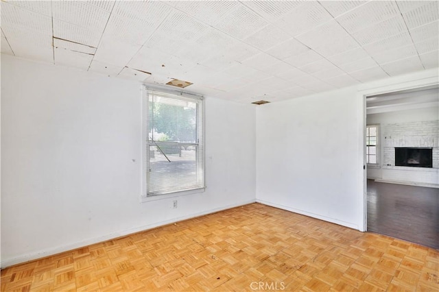 unfurnished room with a brick fireplace and baseboards