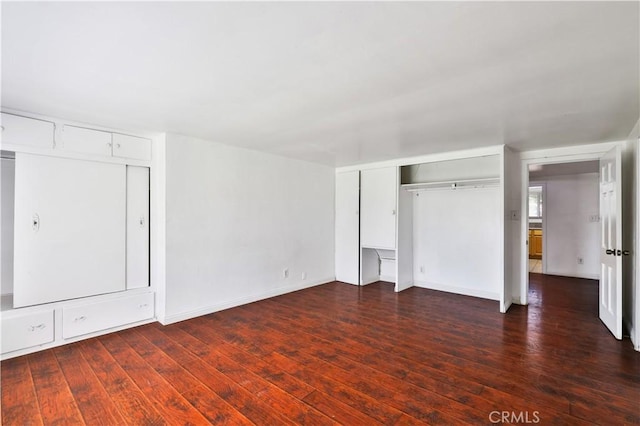 unfurnished bedroom with baseboards and dark wood-style floors