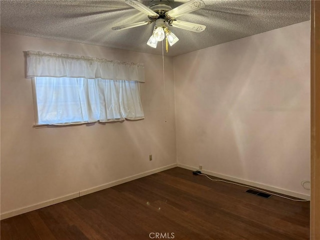 unfurnished room with baseboards, dark wood-style floors, a textured ceiling, a ceiling fan, and visible vents