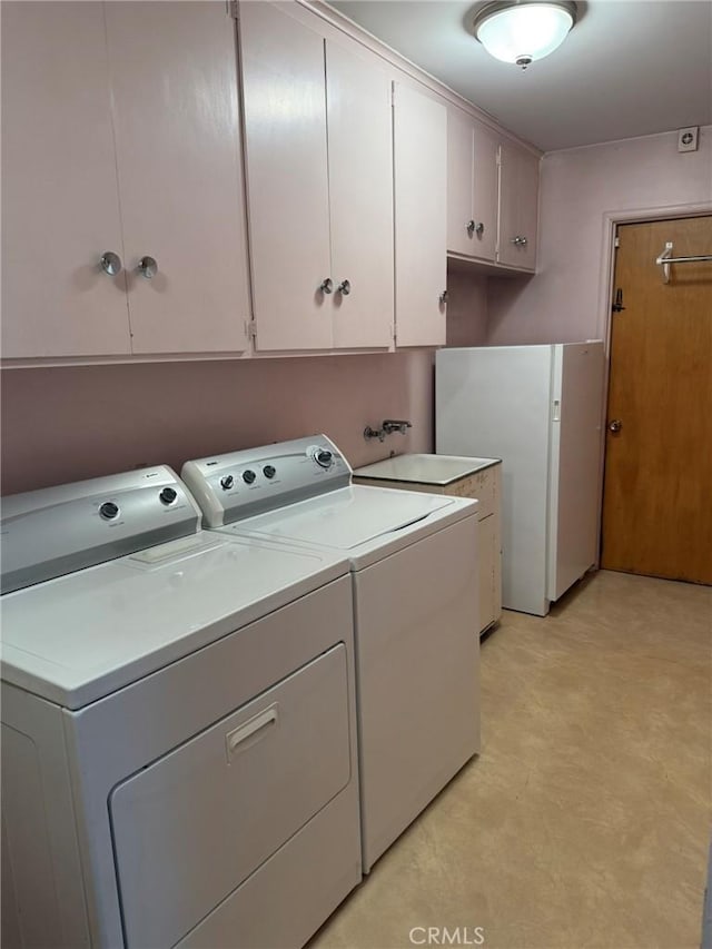 laundry room with washer and clothes dryer, light floors, and cabinet space