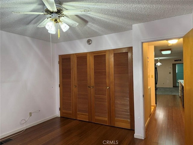 unfurnished bedroom with a textured ceiling, a closet, hardwood / wood-style floors, and visible vents