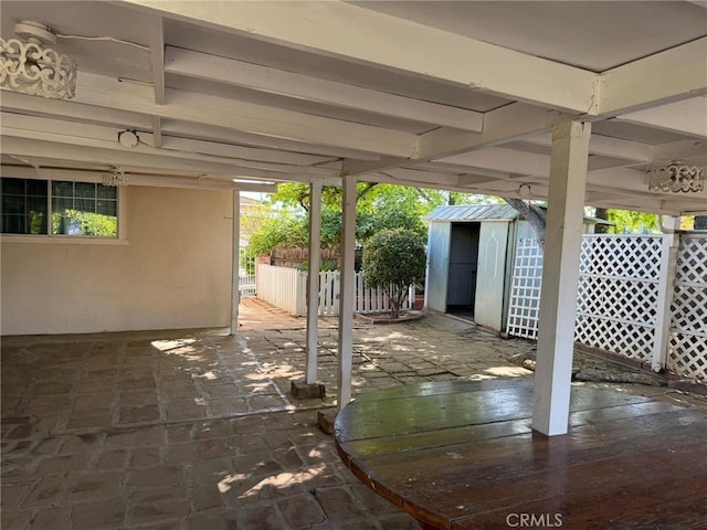 view of patio featuring a storage shed, fence, and an outbuilding