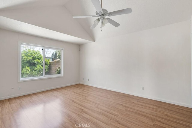 empty room featuring baseboards, light wood-type flooring, vaulted ceiling, and a ceiling fan
