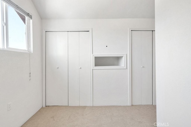 unfurnished bedroom featuring two closets and carpet floors