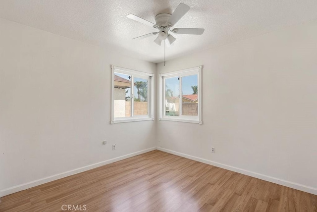 spare room with ceiling fan, light wood finished floors, baseboards, and a textured ceiling