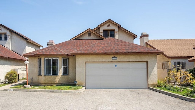 view of front facade featuring aphalt driveway, stucco siding, a garage, and a chimney
