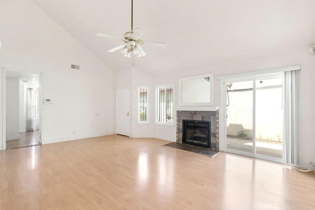 unfurnished living room with light wood-style flooring, a ceiling fan, visible vents, high vaulted ceiling, and a tile fireplace