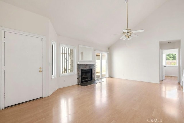 unfurnished living room featuring light wood-style floors, a tile fireplace, a ceiling fan, and lofted ceiling